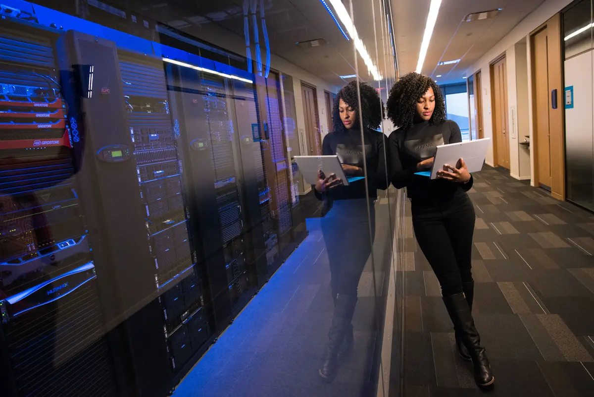 An engineer with a laptop beside server racks in a data centre.