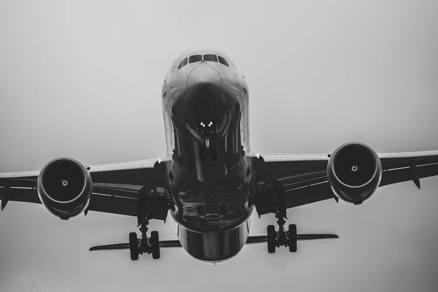 A commercial airliner viewed head-on against an overcast sky.