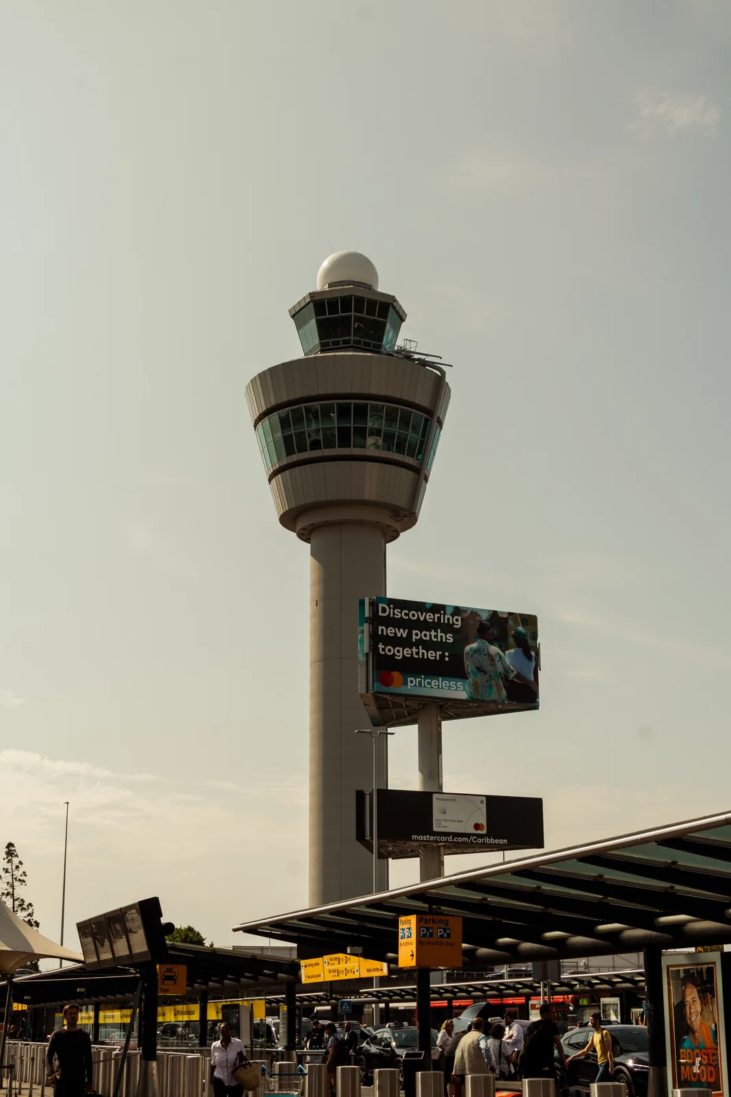 The air traffic control tower at Schiphol Airport against a clear sky.