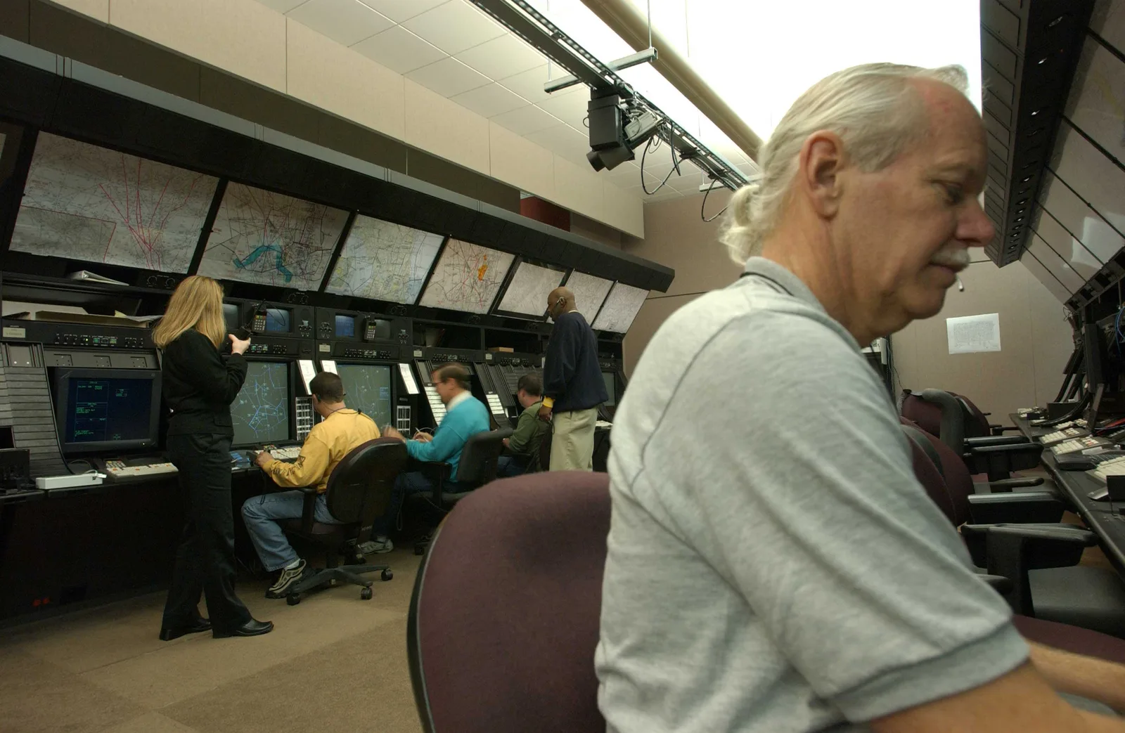 Air-route traffic controllers at radar workstations on an operations floor.