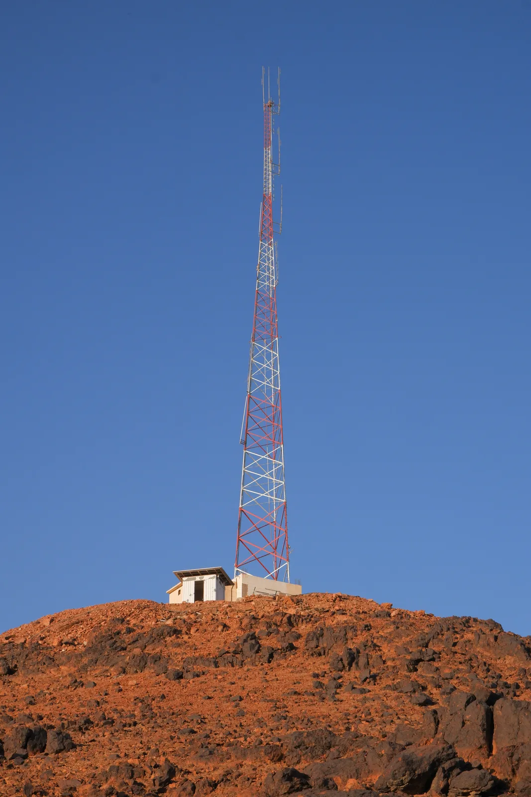 A radio tower standing on a rocky hillside.