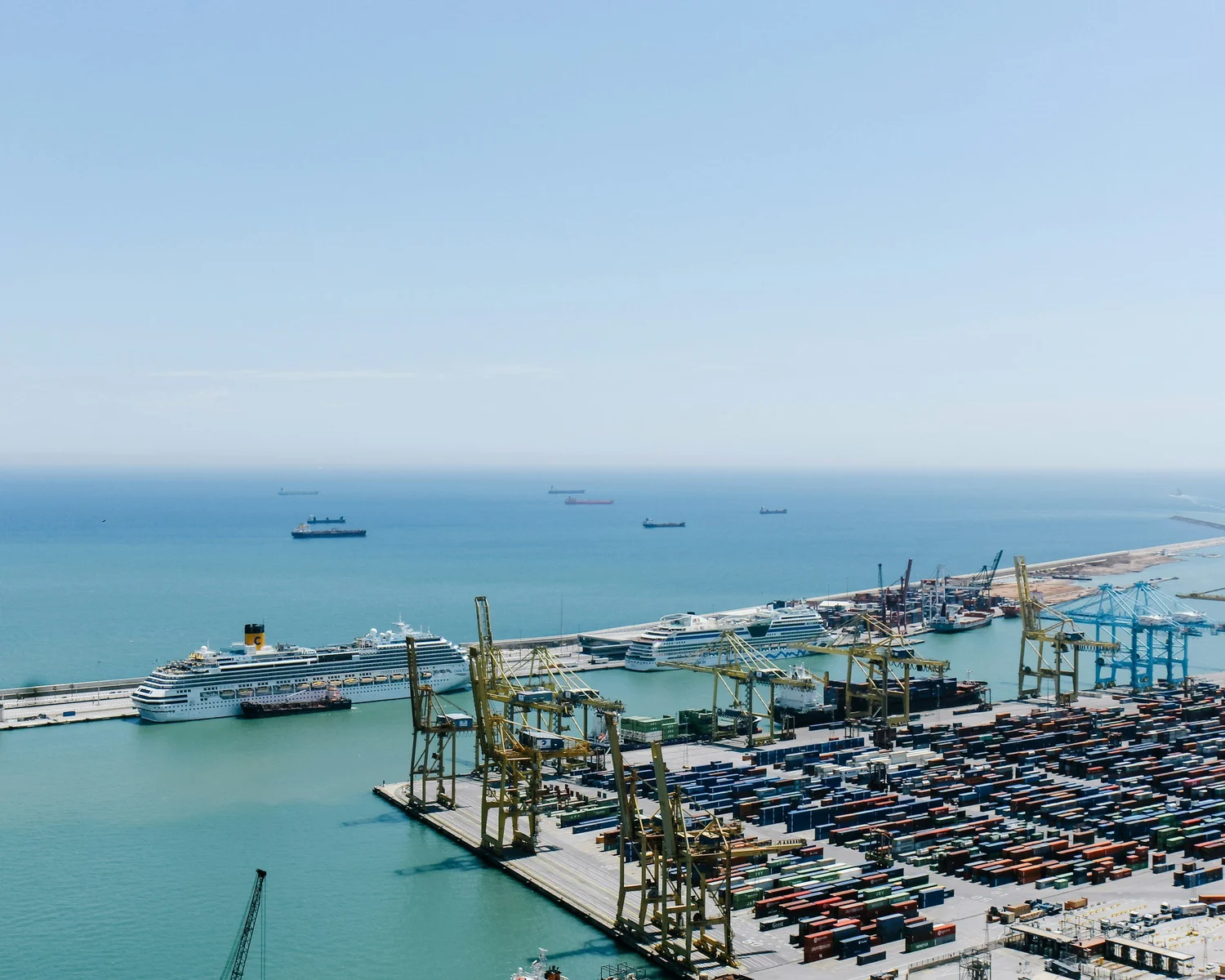 An aerial view of a container port with gantry cranes and ships at berth.