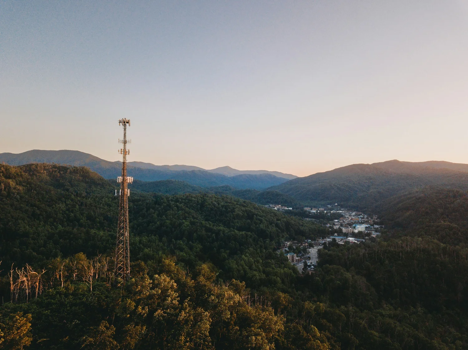 A tall communications tower against a mountainous landscape.