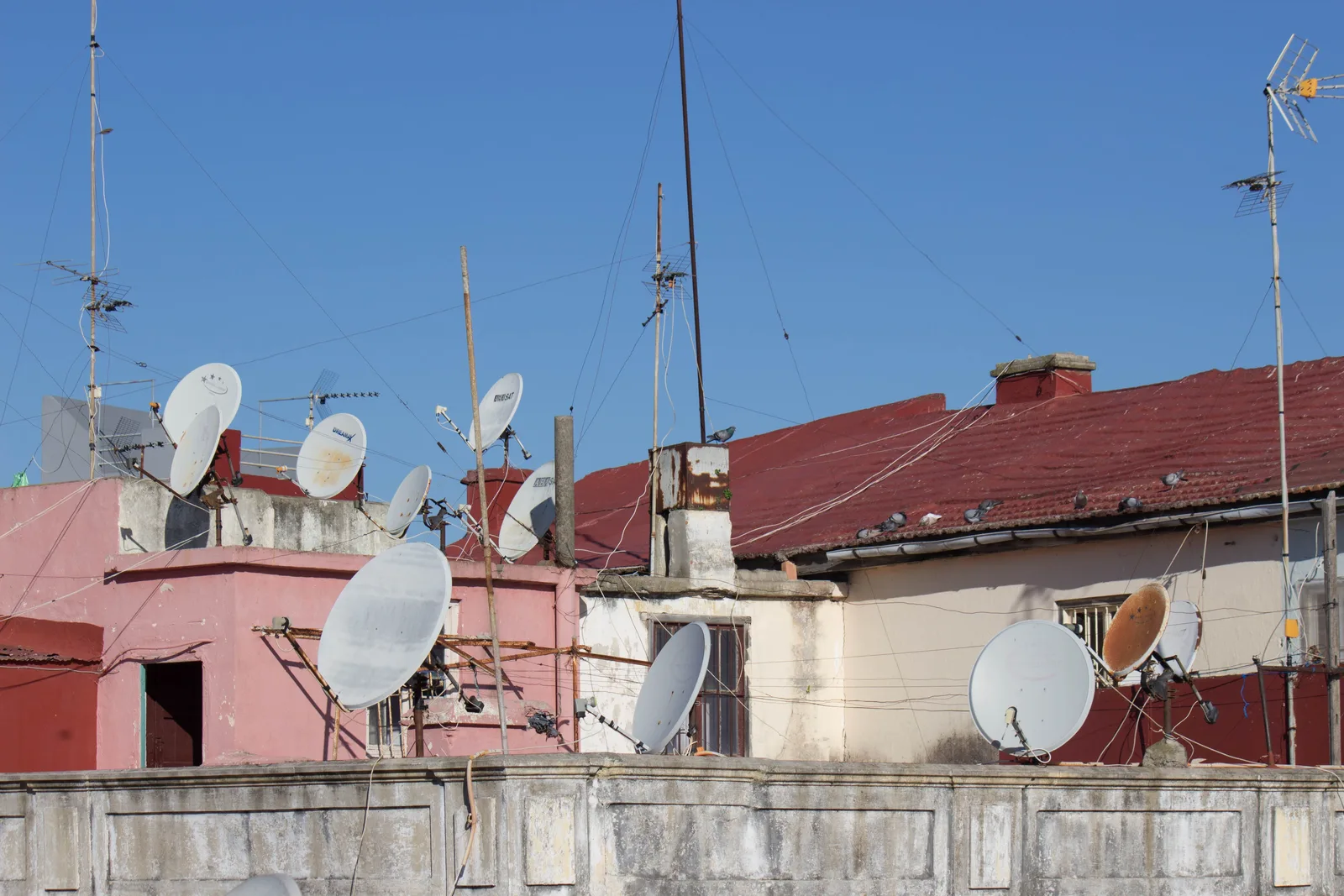 A rooftop crowded with satellite dishes and antennas above a dense city.