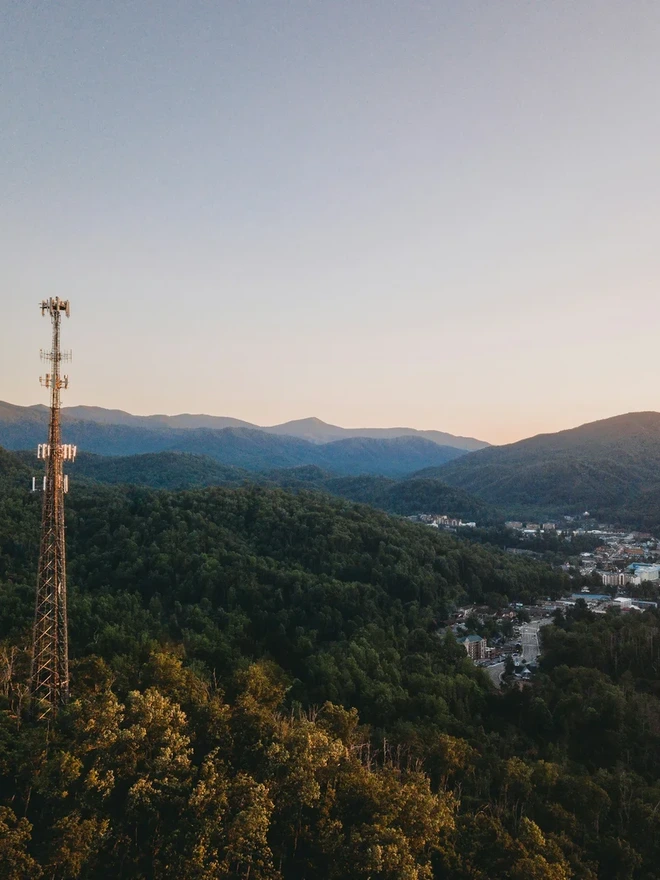 A tall communications tower against a mountainous landscape.